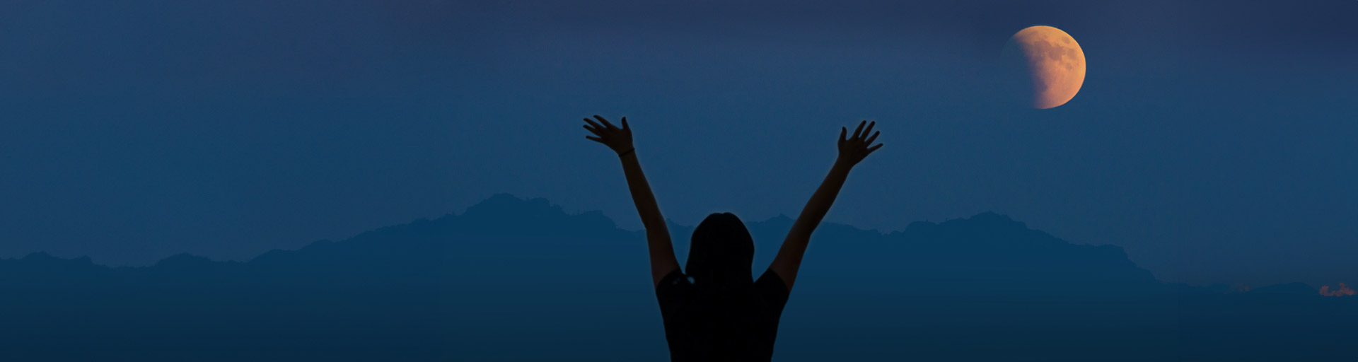 silhouette of a person in front of mountains and the moon